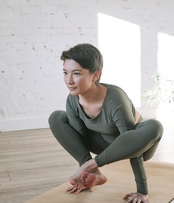 Woman in a calm yoga pose in a bright room.